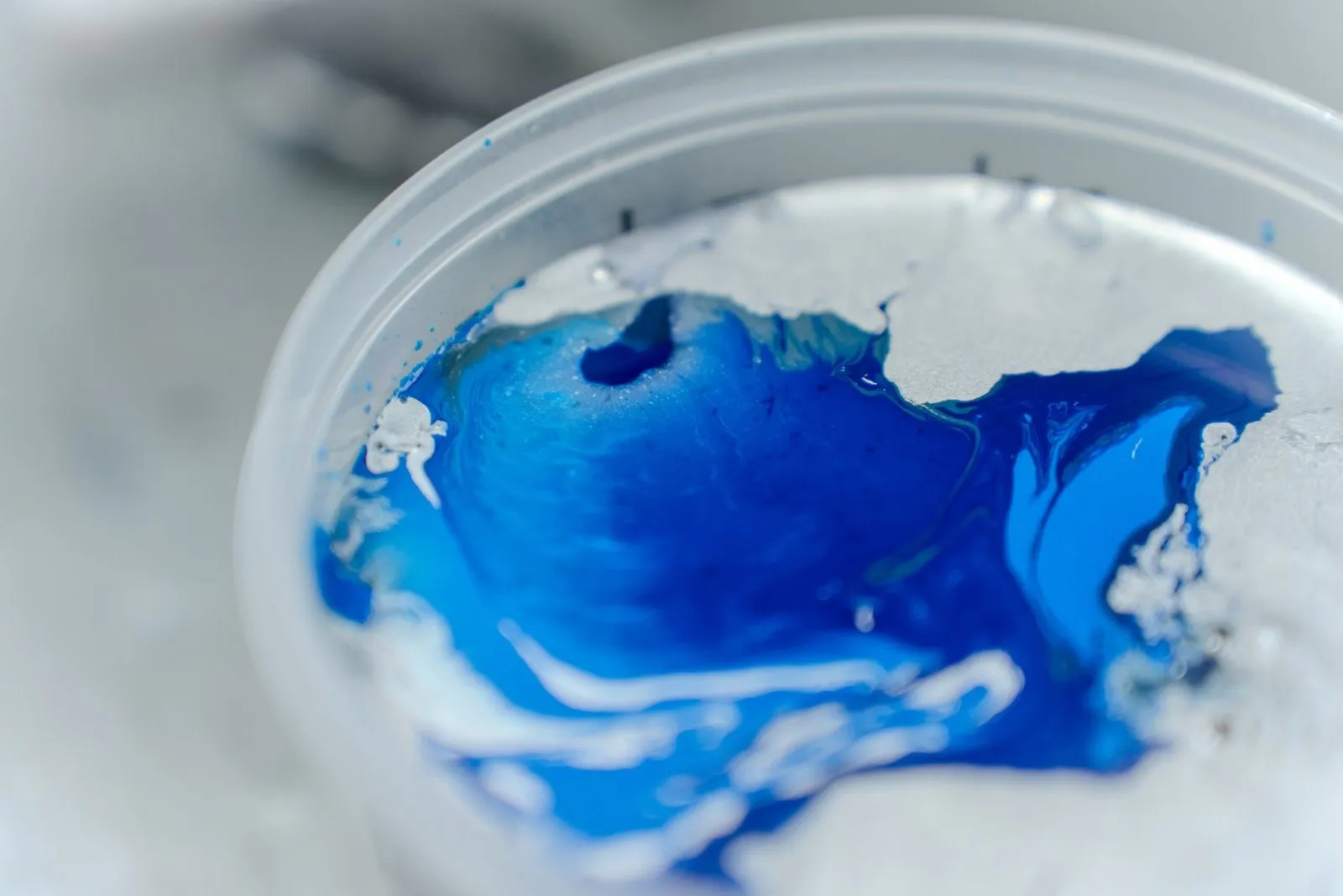 Detalle de pintura azul recién mezclada en el vaso de la pistola